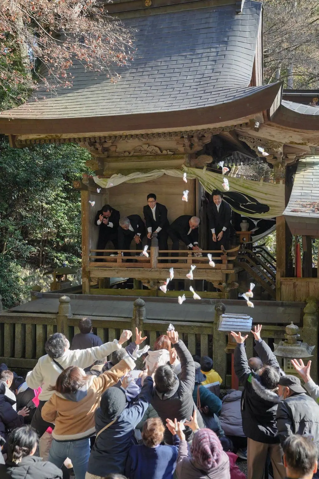 霜月祭の餅投げ。拝殿からまかれる餅に手を伸ばす人たち