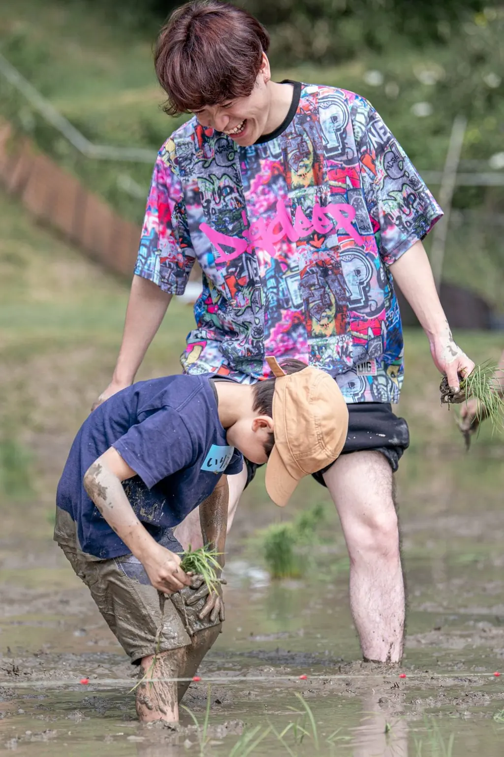 田んぼで、笑いながら苗を植える女性