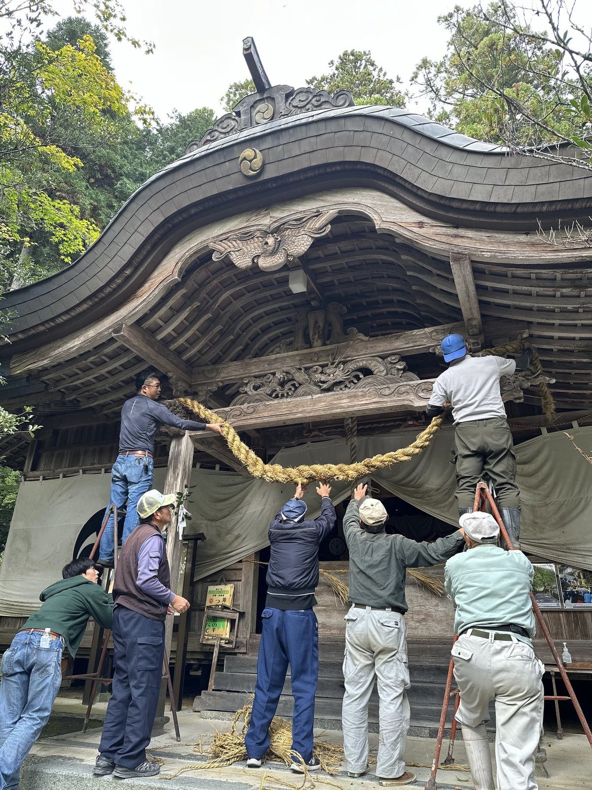 大津神社の拝殿にしめ縄をかける人たち