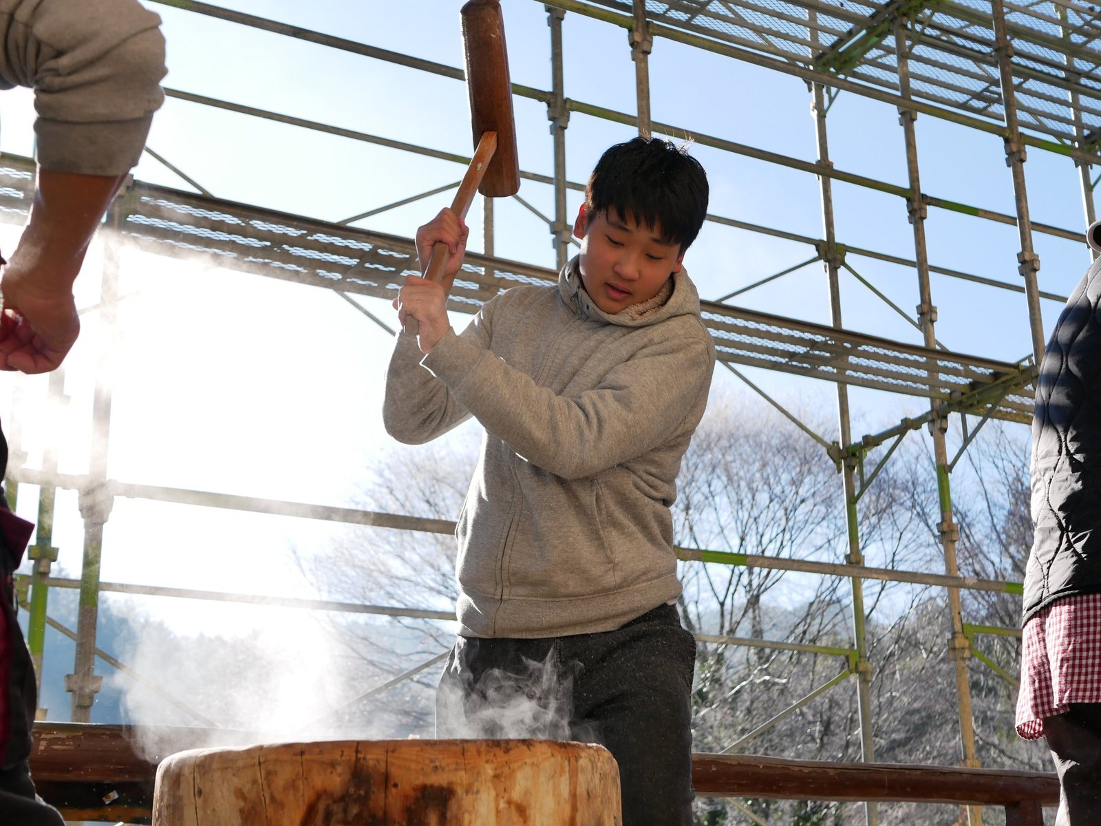 湯気の立つ臼に向かって、杵を振り上げる若者