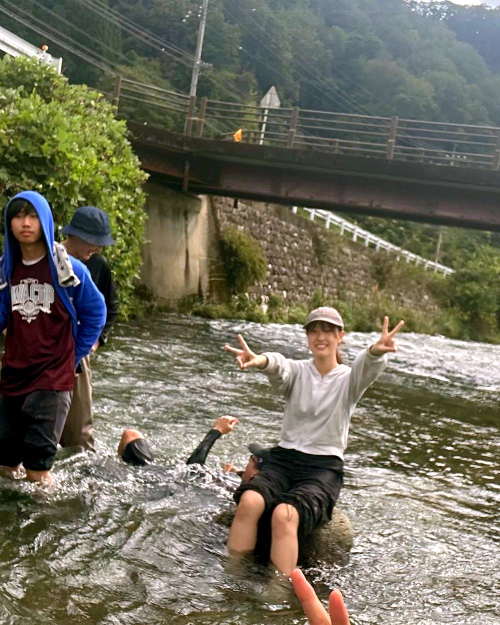 川の中でピースをする若者たち