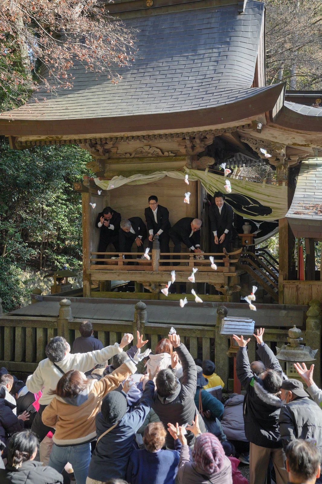 霜月祭の餅投げ。拝殿からまかれる餅に手を伸ばす人たち